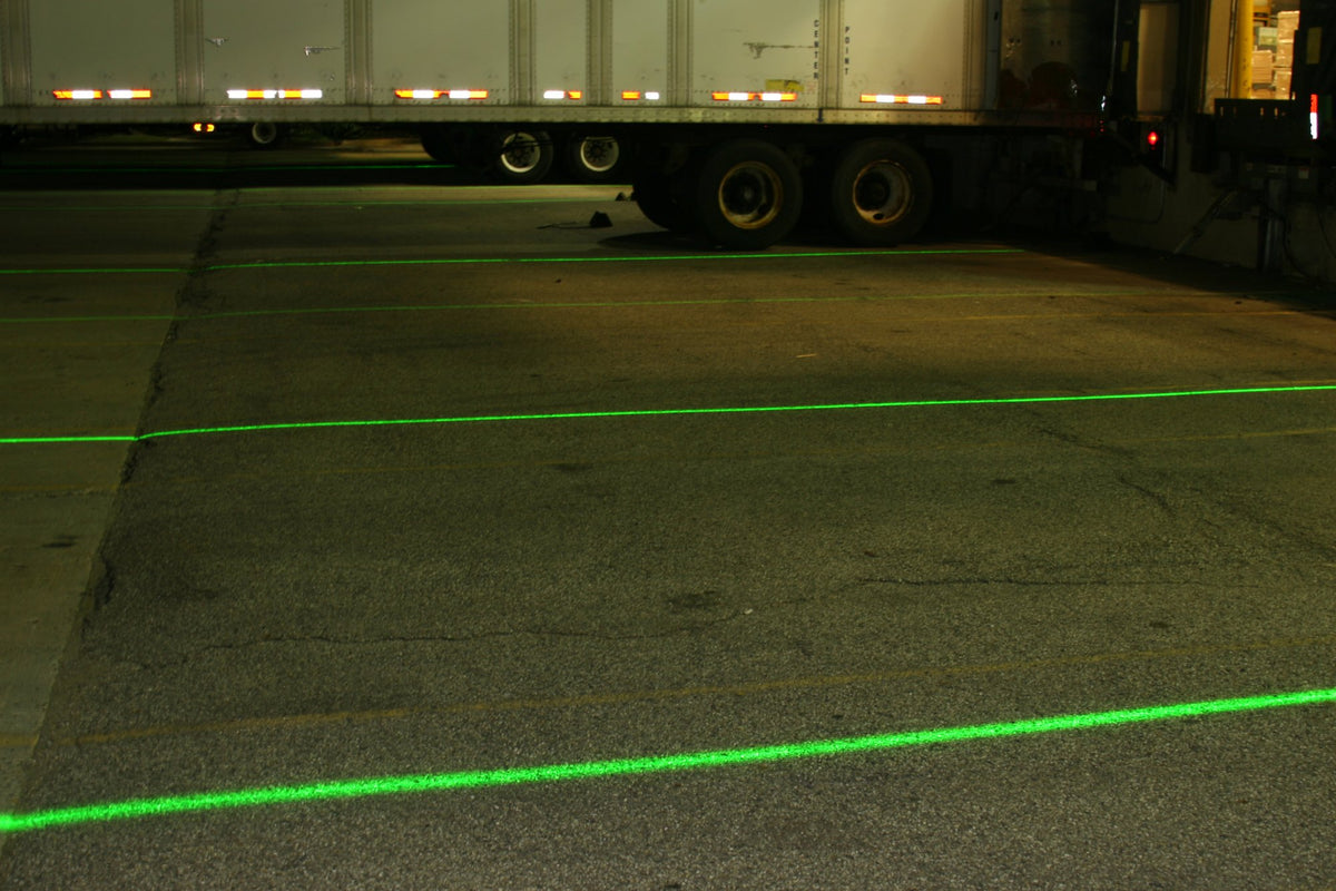 Green DockRight laser lines guiding trucks at an exterior loading dock at night