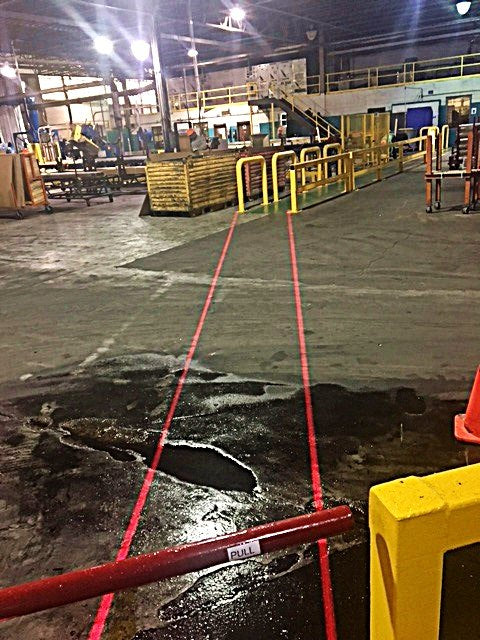 Red DockRight laser walkway lines staying visible on wet and dry warehouse floor