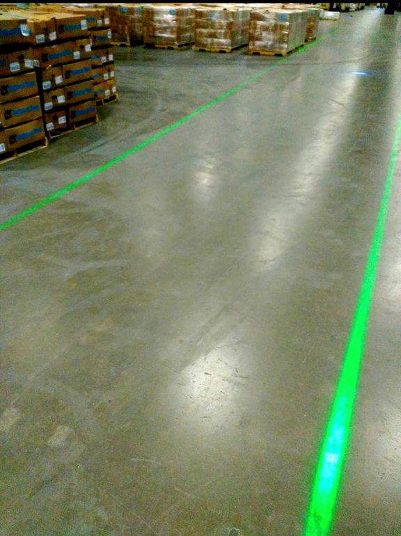 Green DockRight laser line visible in a brightly lit warehouse aisle