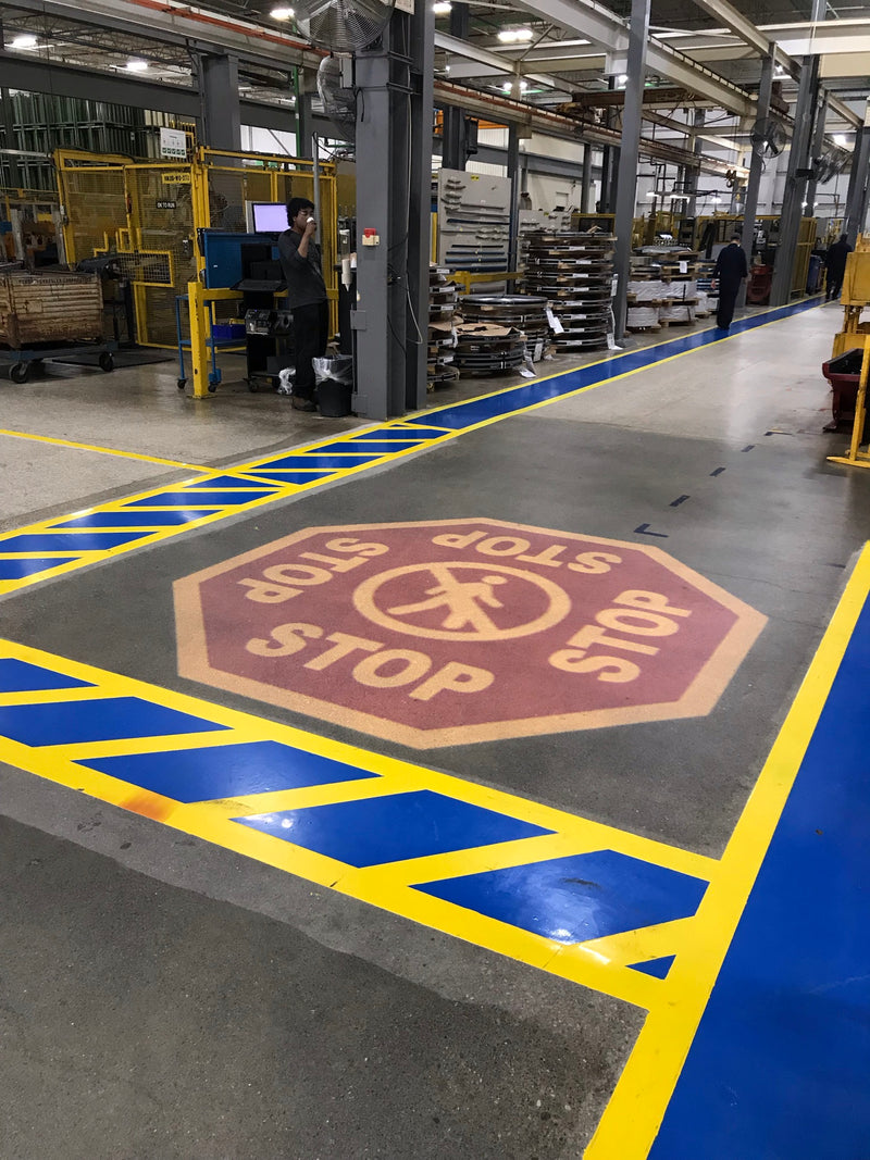 Yellow and blue floor marking zones and a STOP marker on a plant floor
